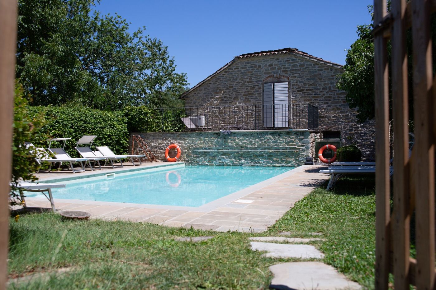 La piscina nel giardino, con il casale in pietra sullo sfondo