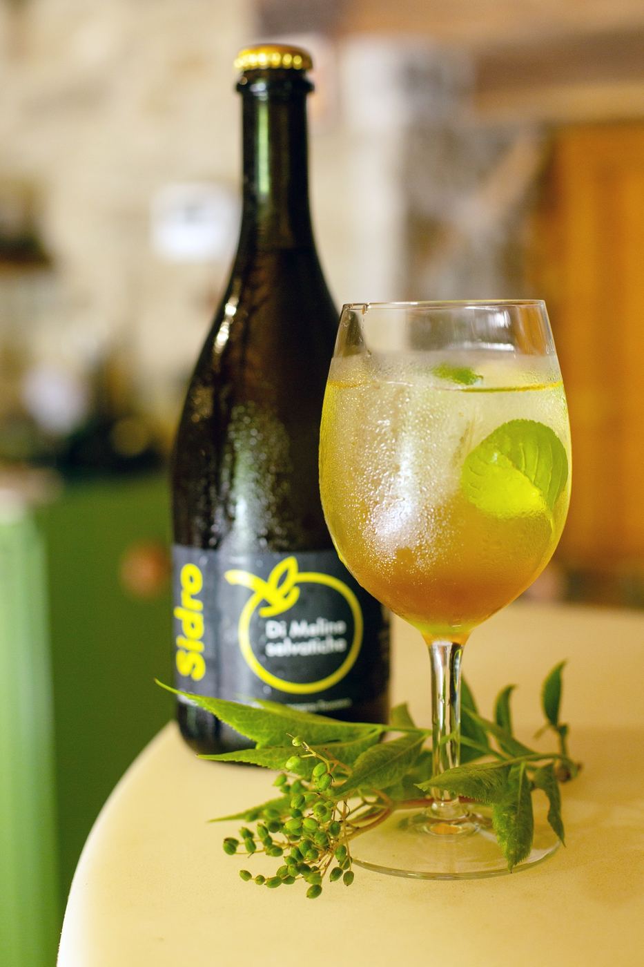 Bottiglia e calice con una bevanda fresca guarnita di erbe